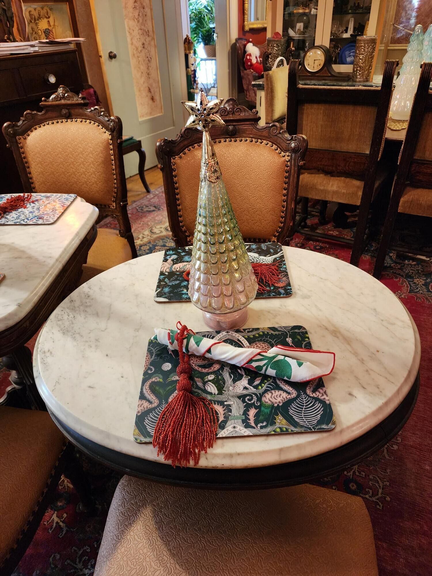 Una mesa redonda de mármol con un jarrón de cristal decorativo y un regalo envuelto con un lazo rojo.
