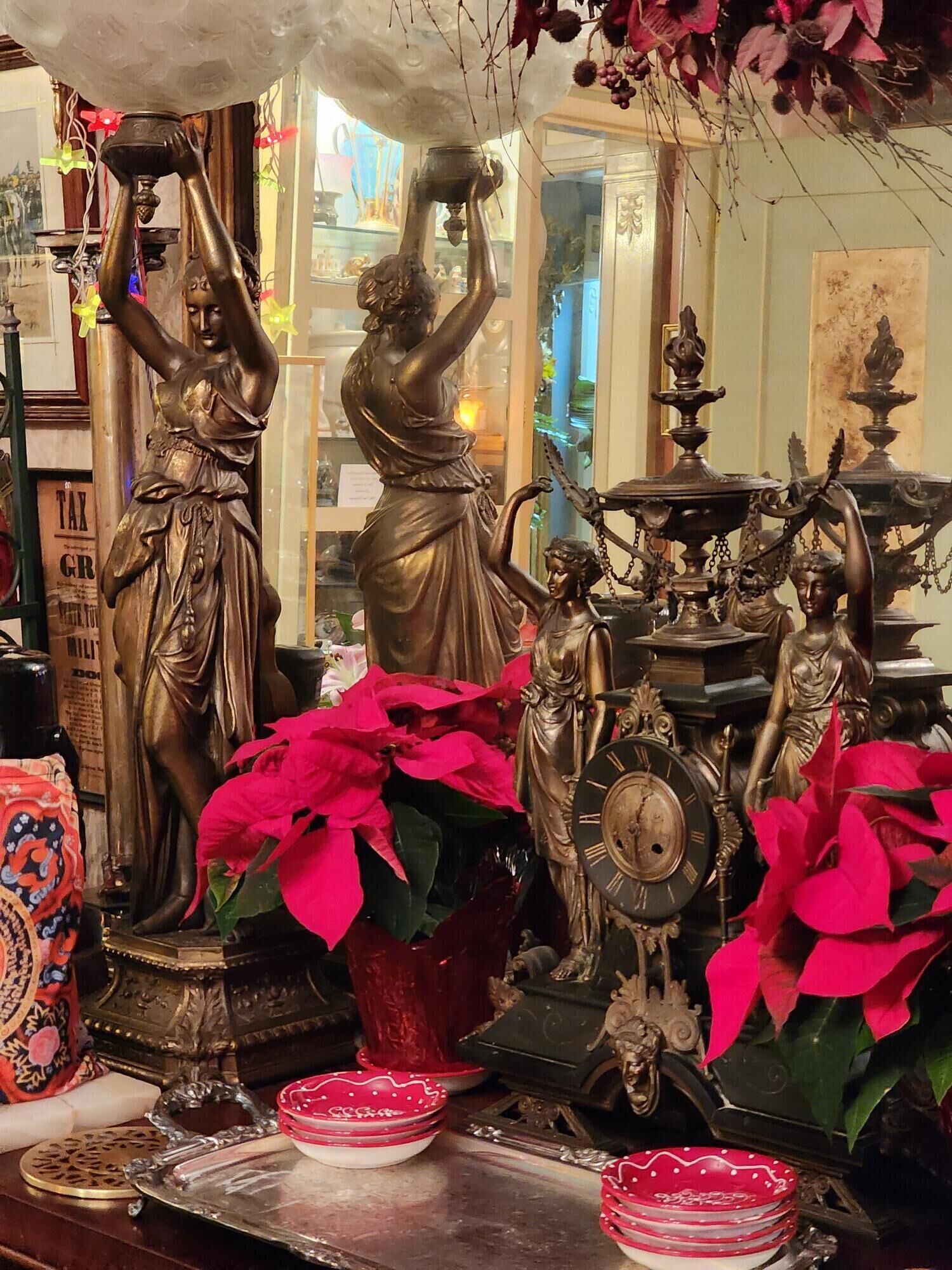 Une pièce où se trouve une grande statue d’une femme tenant une cruche, entourée d’autres statues et d’une horloge.
