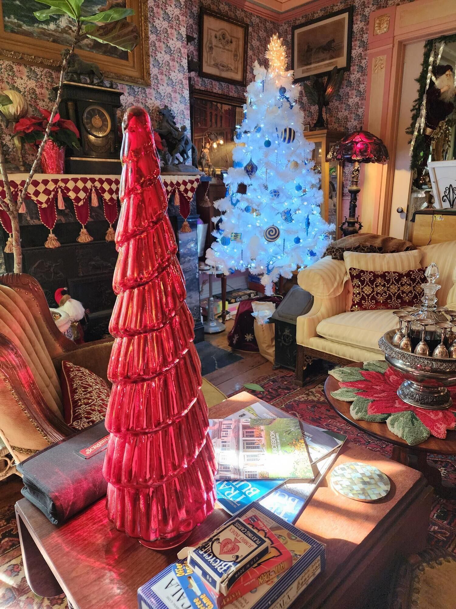 Un salon chaleureux avec un sapin de Noël blanc, un sapin de Noël rouge et une cheminée.