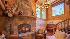 A cozy interior with a stone fireplace, leather furniture, and a wooden staircase.