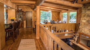 A wooden interior with a dining area, kitchen, and a stone wall.