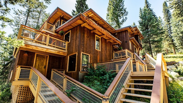 A wooden cabin with multiple levels, a balcony, and a staircase leading to the entrance.
