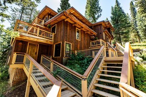 A wooden cabin with multiple levels, a balcony, and a staircase leading to the entrance. - Jackson Hole Hideout (Wilson)