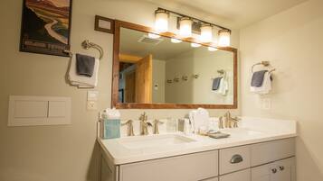 A bathroom with a double sink, a large mirror, and a poster of Grand Teton National Park.