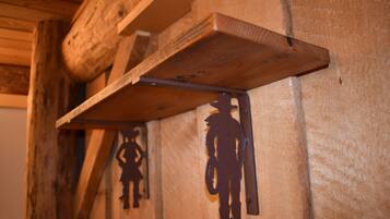 Un muro in legno rustico con staffe metalliche e le sagome di un cowboy e un bambino.