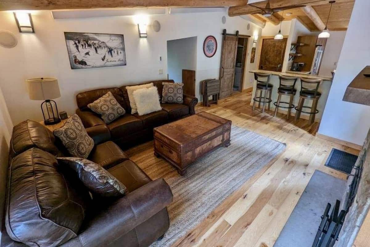 Una sala de estar acogedora con un sofá de cuero marrón, una mesa de centro de madera y un cuadro en la pared.