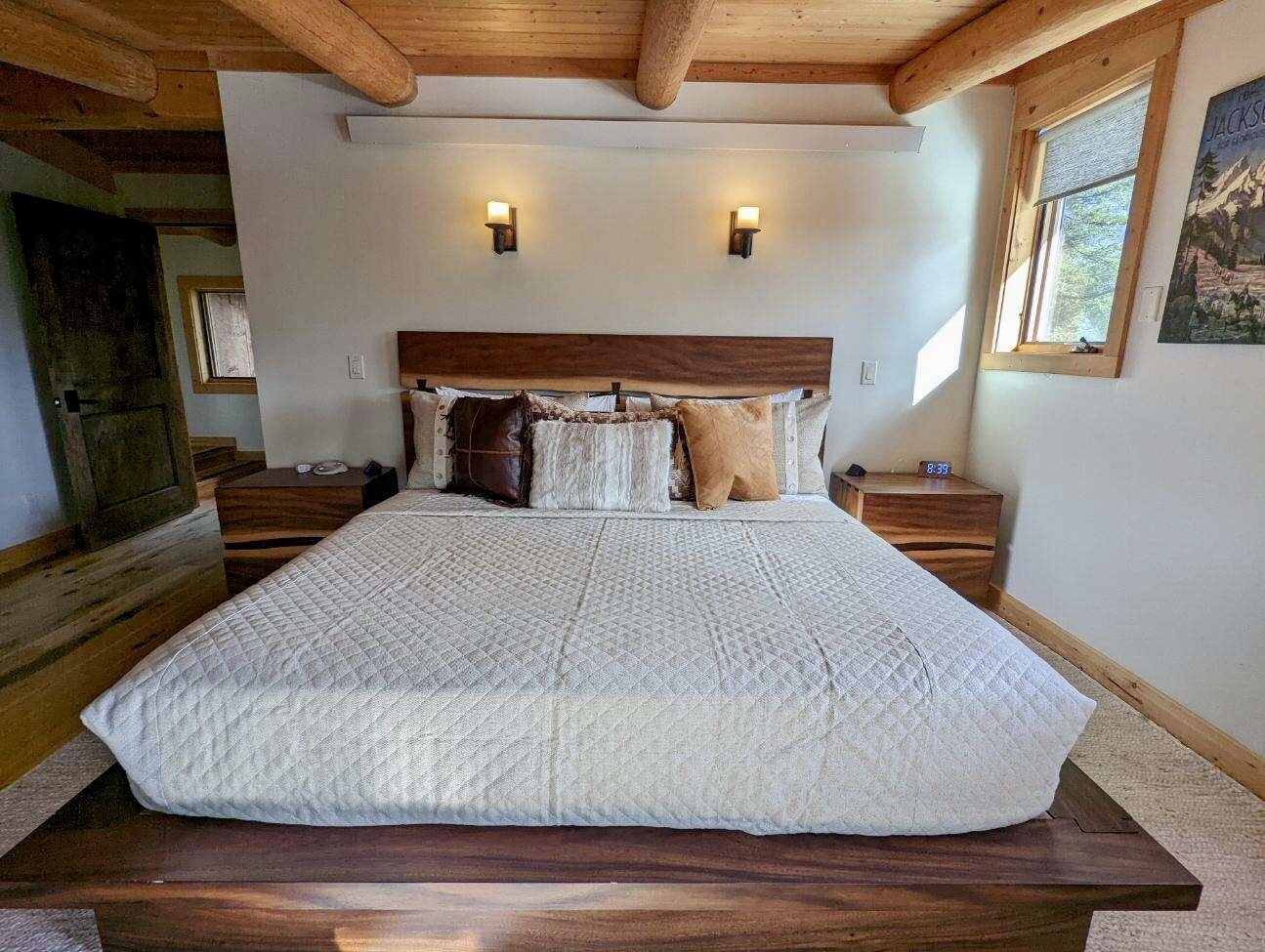 A large bed with a quilted white bedspread, wooden headboard, and two bedside tables with lamps.
