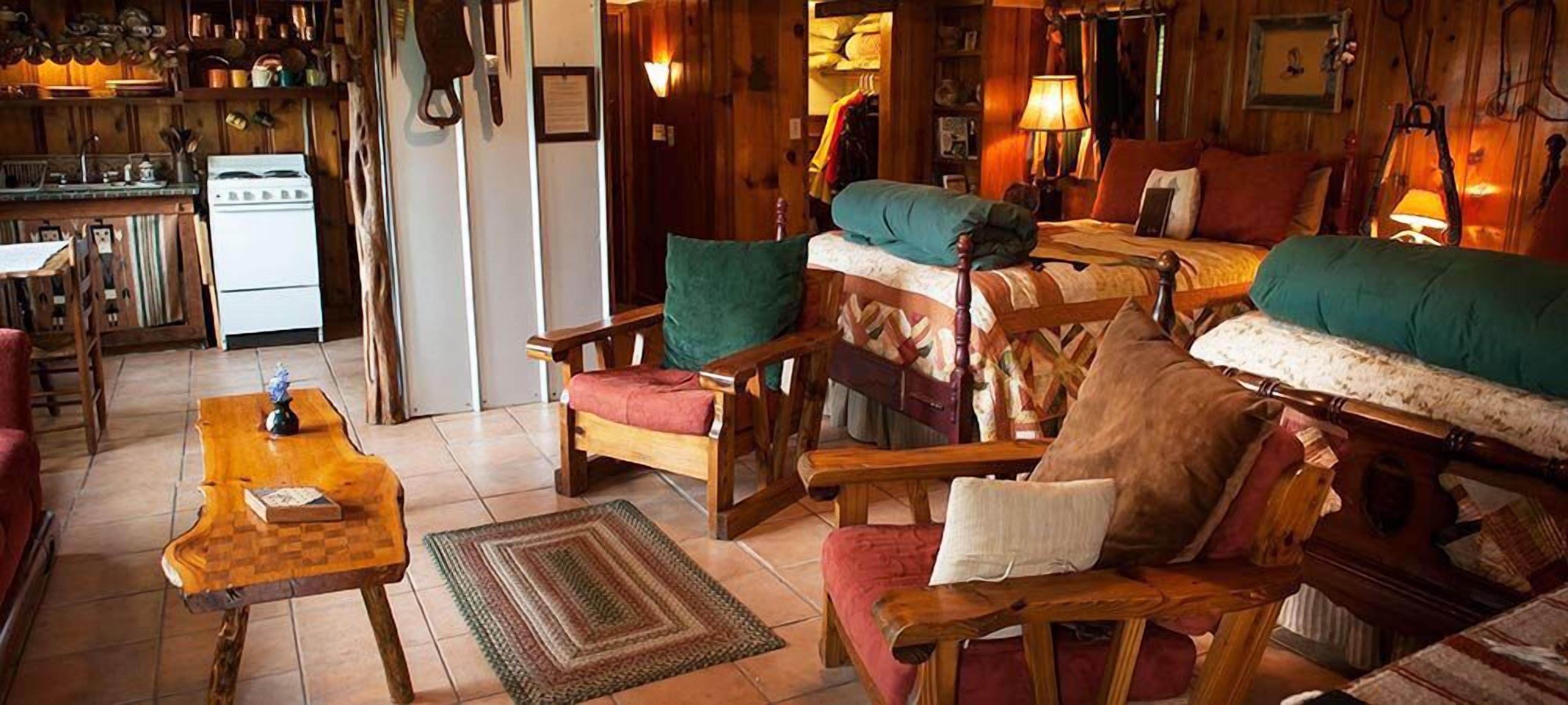 A cozy room with a wooden sofa, a wooden chair, a small table, and a bed with a quilt.