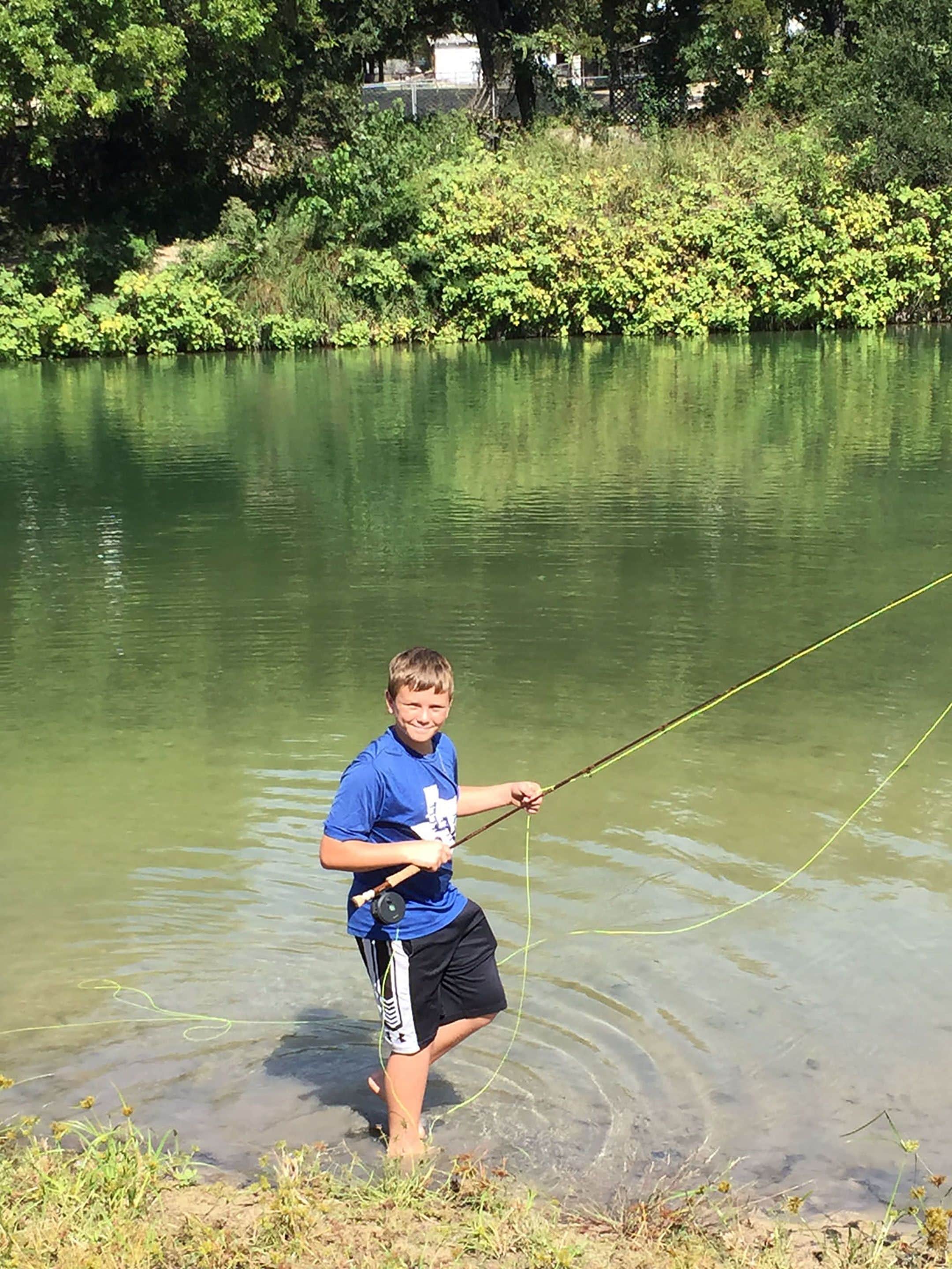 Una persona pescando en un lago tranquilo rodeado de abundante vegetación.
