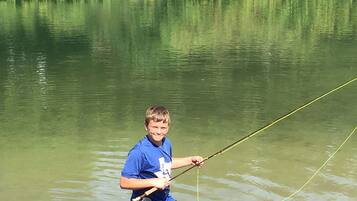 Una persona pescando en un lago tranquilo rodeado de abundante vegetación.