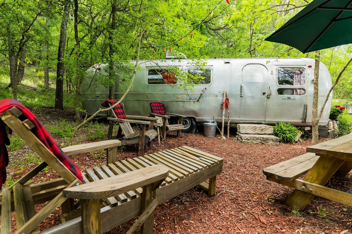 A campsite with a camper, picnic tables, and chairs.