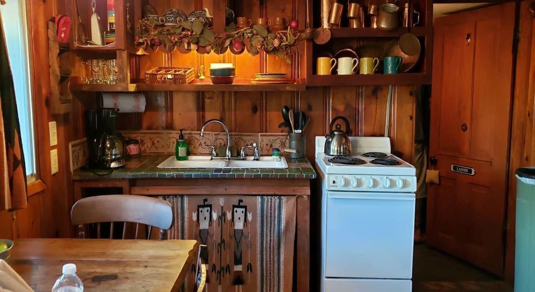 A wooden kitchen with a stove, sink, and various kitchen utensils.