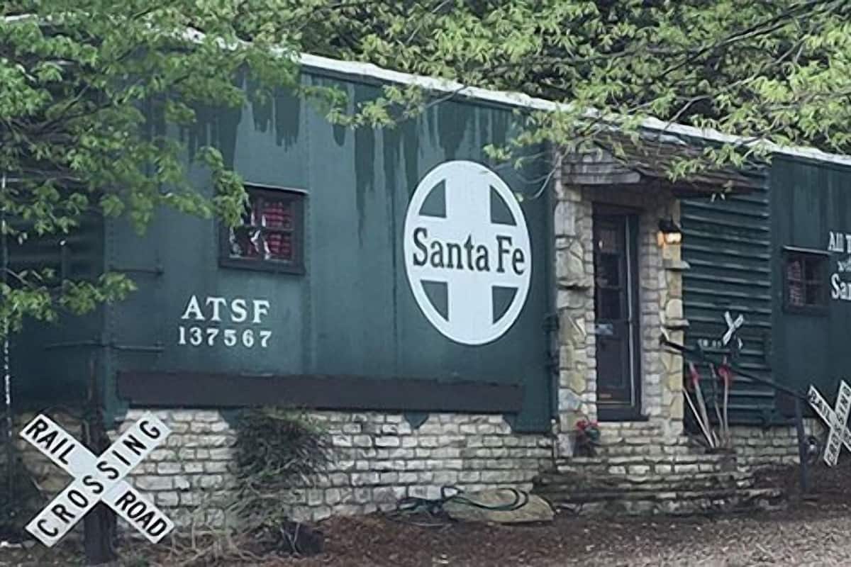 A small, rustic building with a Santa Fe logo and a sign reading "All The Mary with Santa Fe."