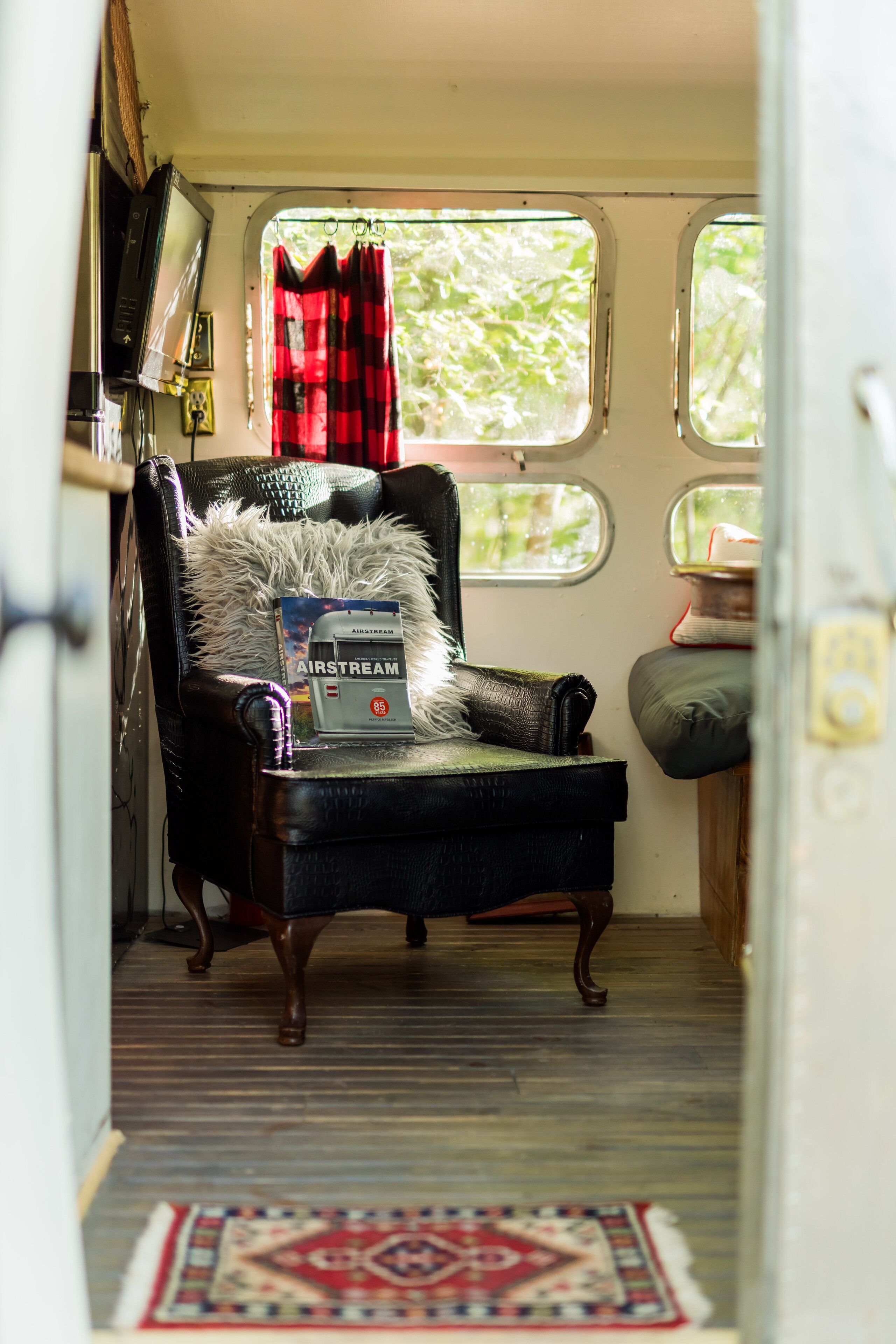 A cozy interior with a leather armchair, a small rug, and a window with curtains.