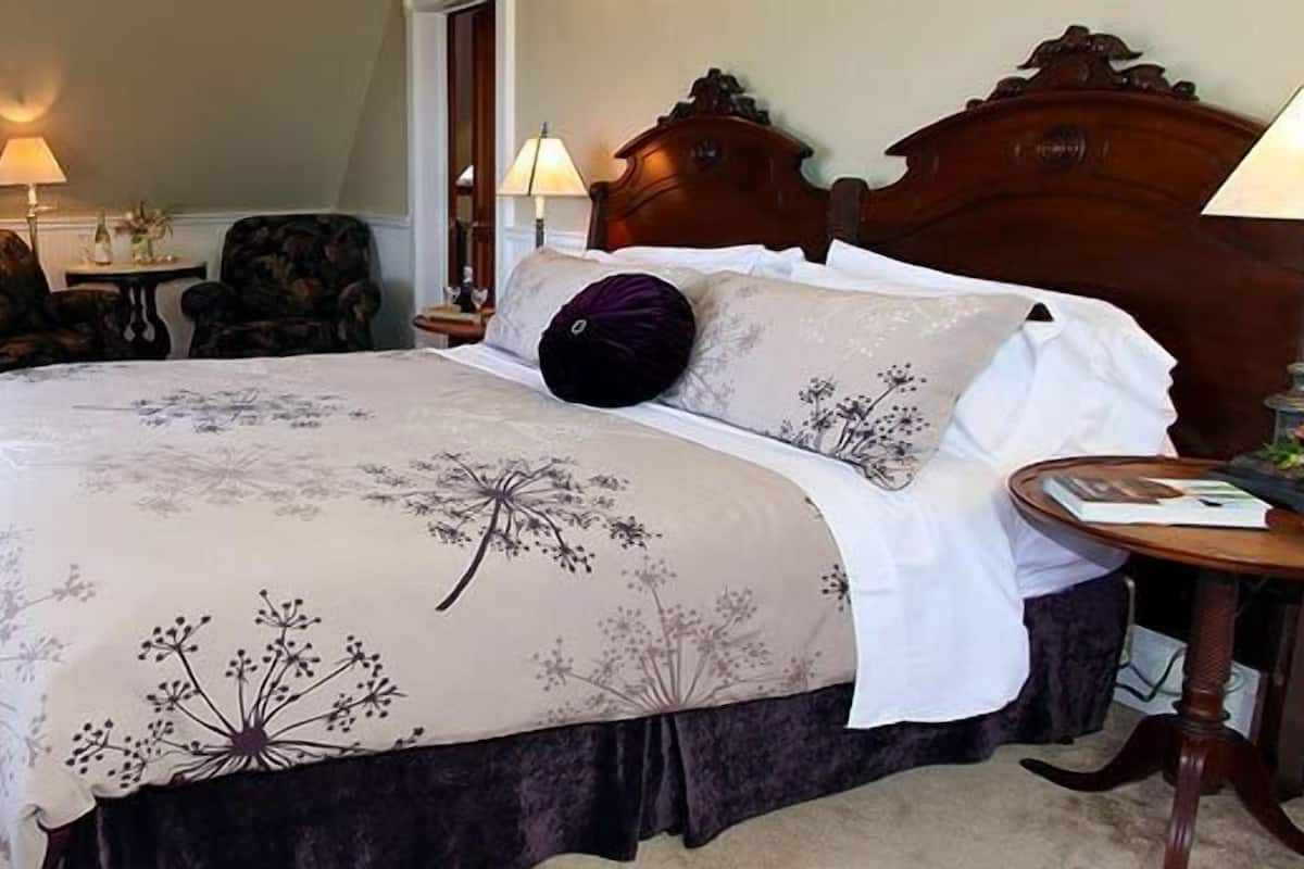 A bedroom with a large bed, two bedside tables, a chair, and a radiator.