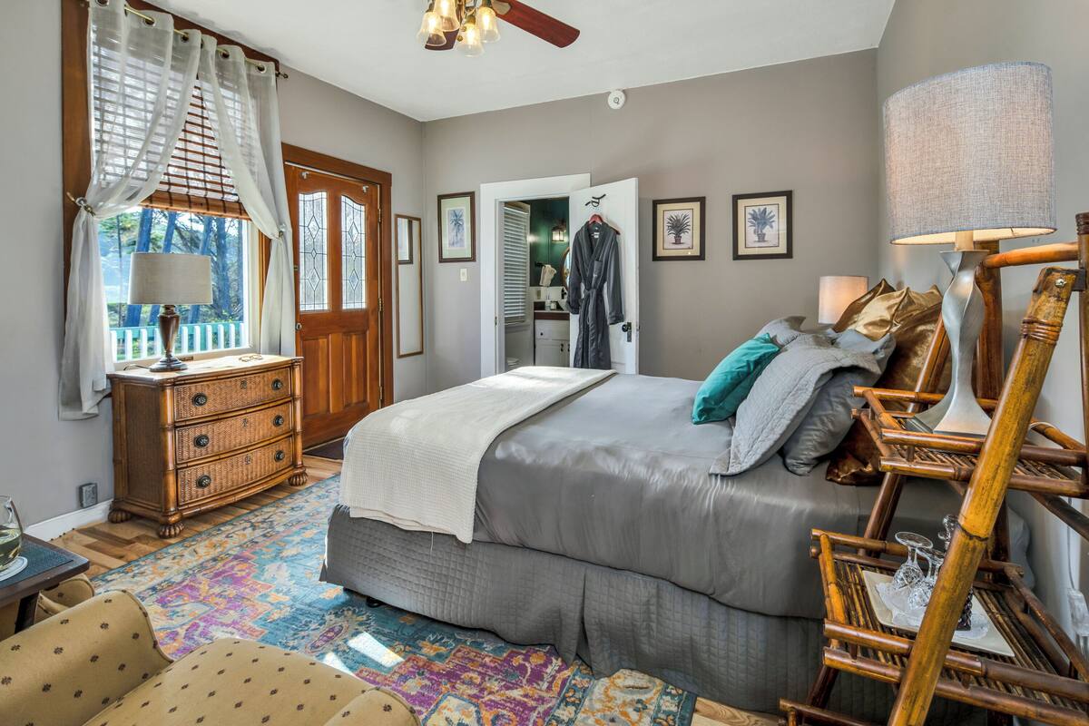 A bedroom with a large bed, a dresser, a chair, and a lamp.
