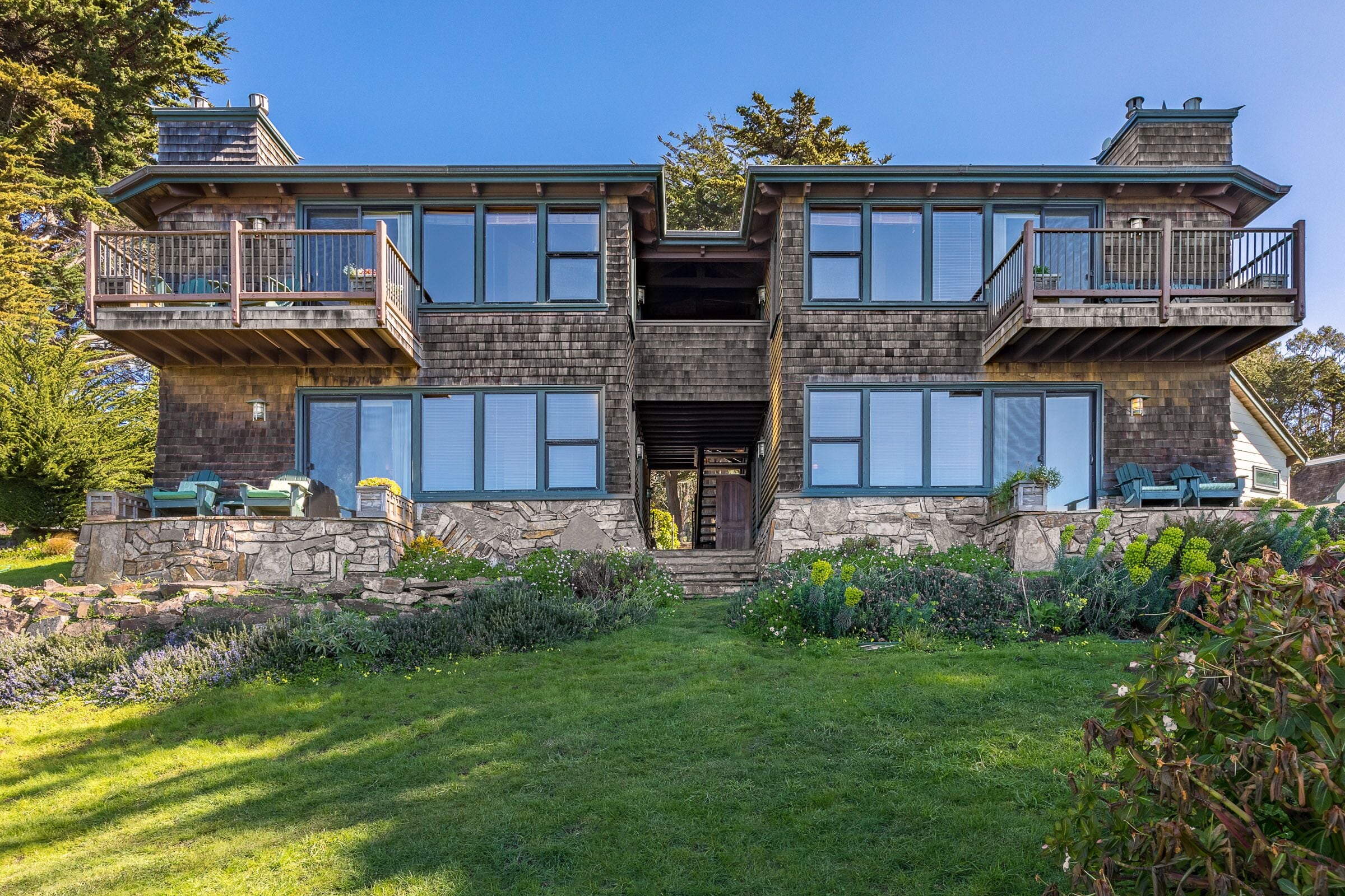 A two-story house with a stone facade, large windows, and a central entrance.