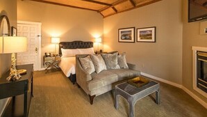 Una habitación acogedora con una cama, un sofá, una mesita y una chimenea.