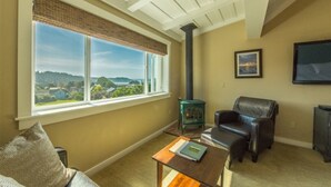 Una sala de estar con un ventanal grande, chimenea, sofá de cuero y televisor.