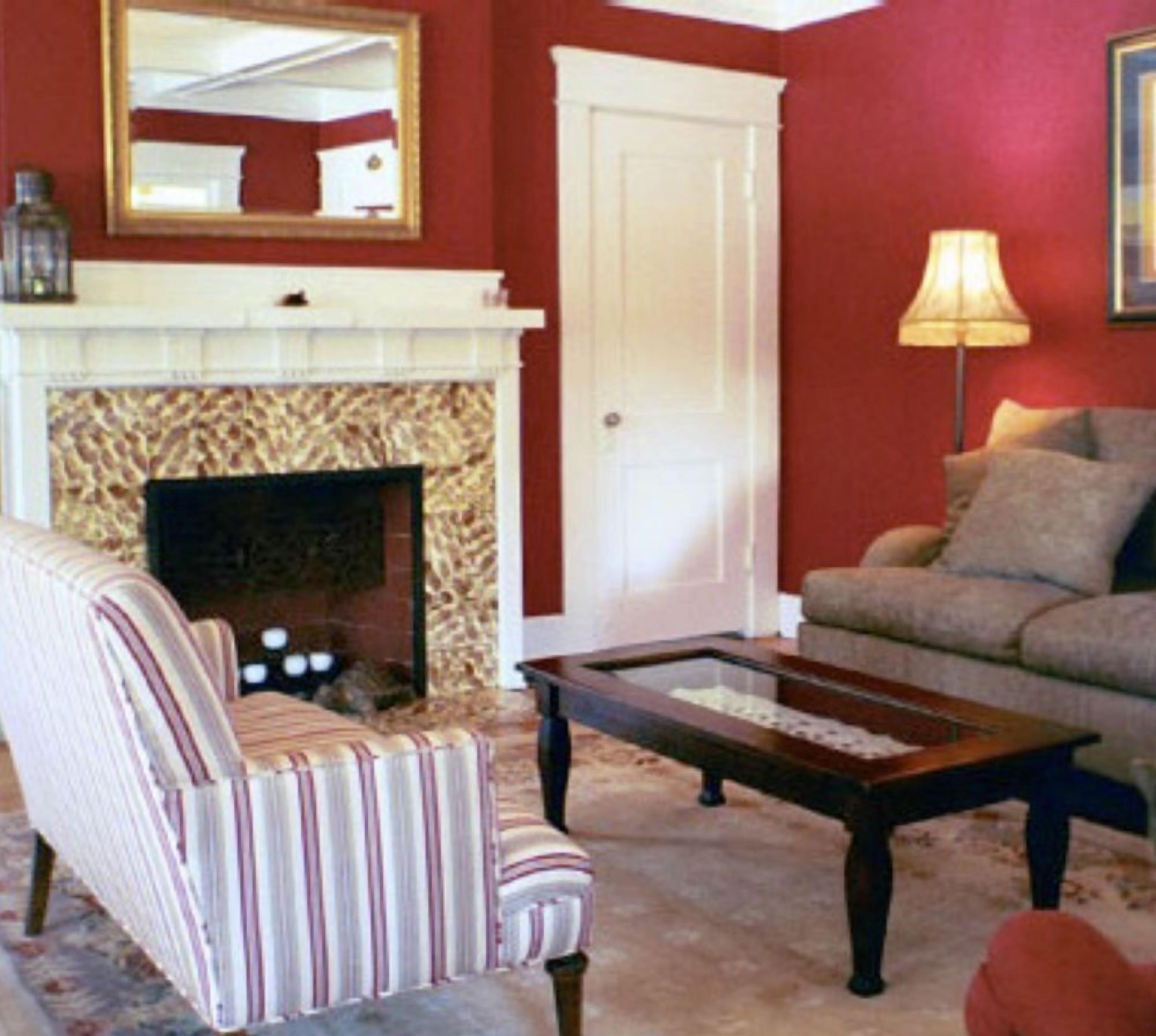 A living room with a striped armchair, a sofa, a coffee table, a fireplace, and a lamp.