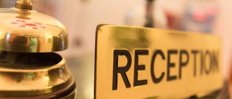 Un mostrador de recepción con un cartel que dice "RECEPTION" y una campana.