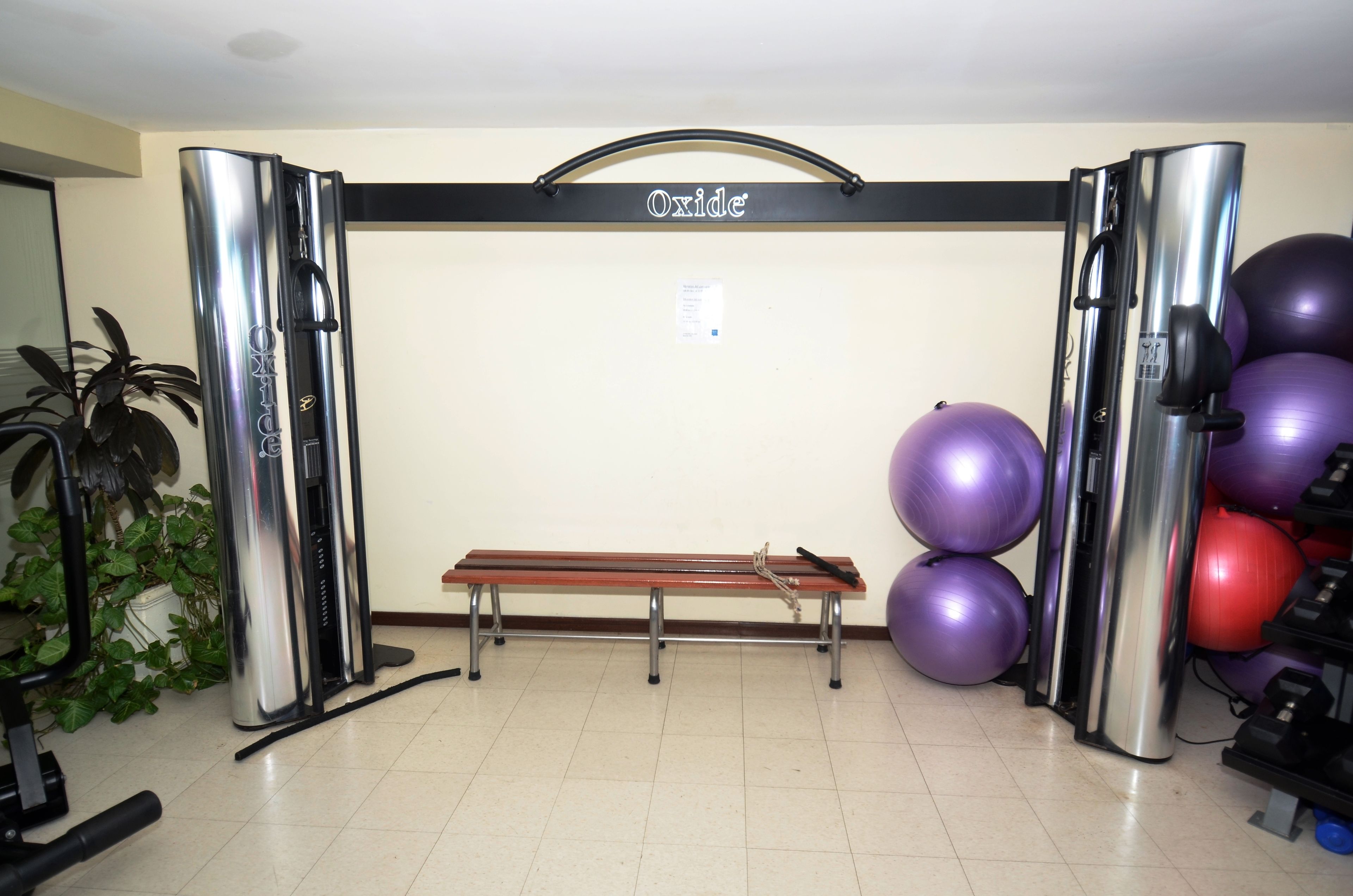 A gym with a bench, exercise balls, and a wall-mounted sign.