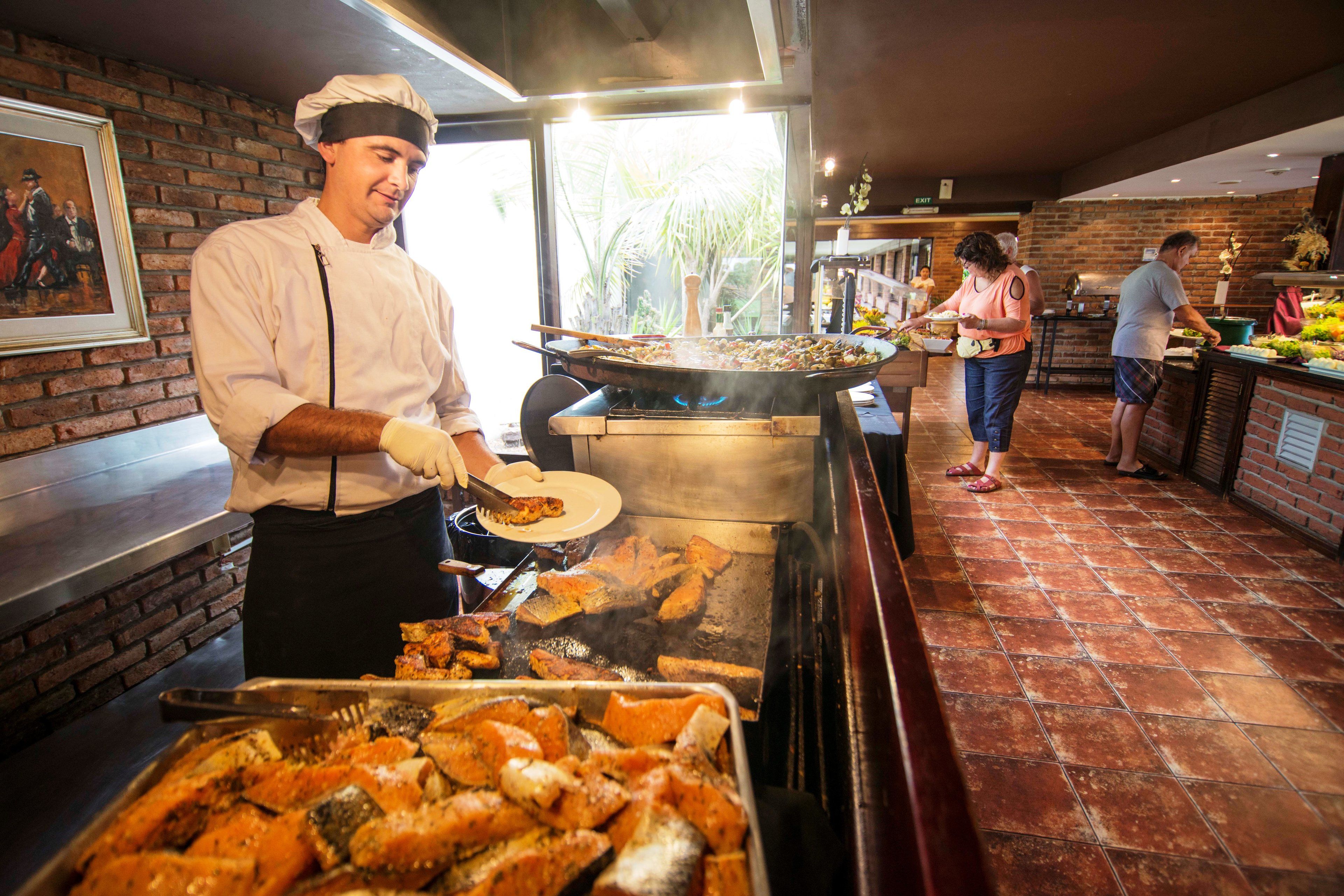 A restaurant with a brick wall, a large grill, and a buffet area.