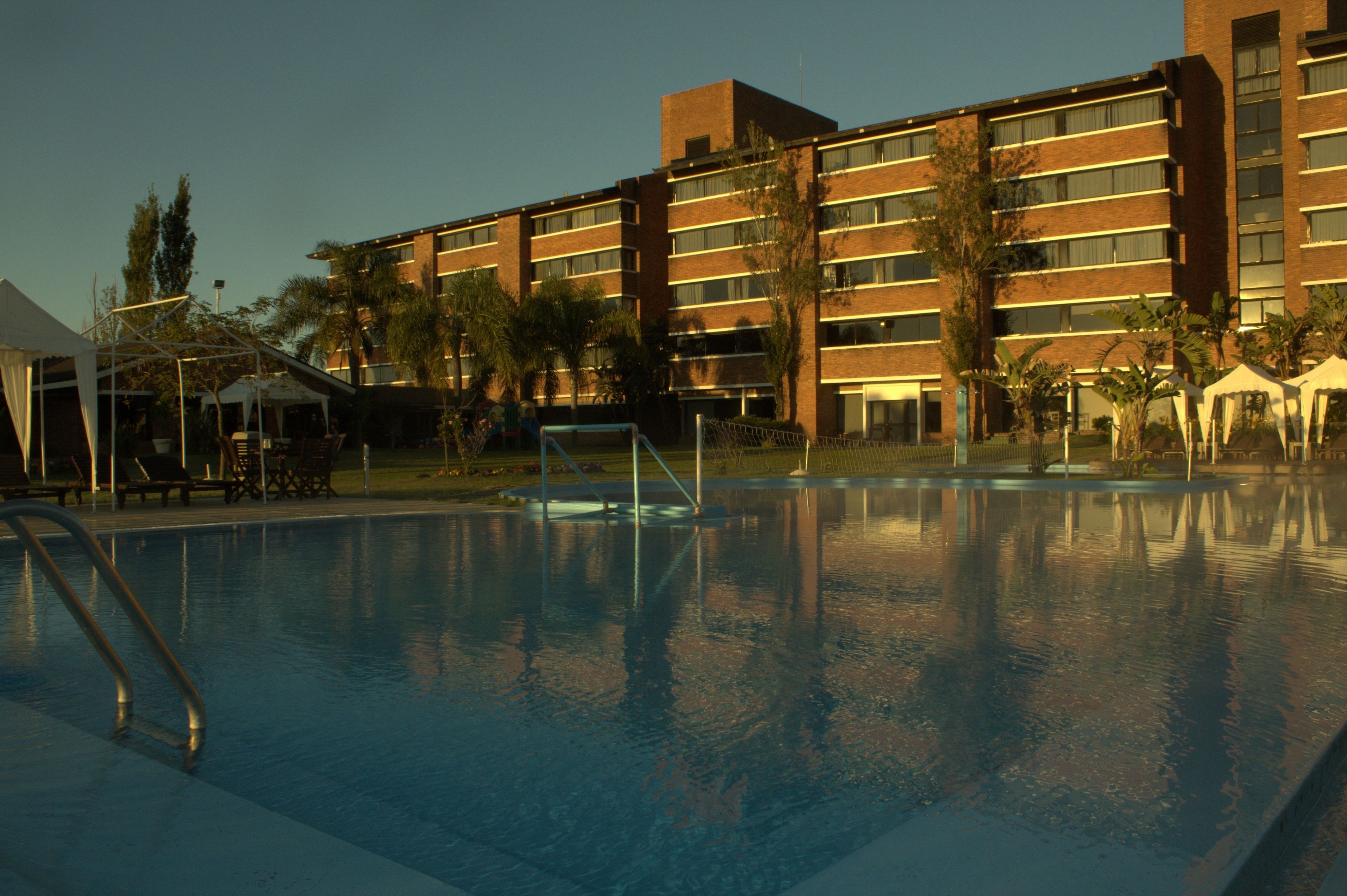 A swimming pool with a clear view of a multi-story hotel building in the background.