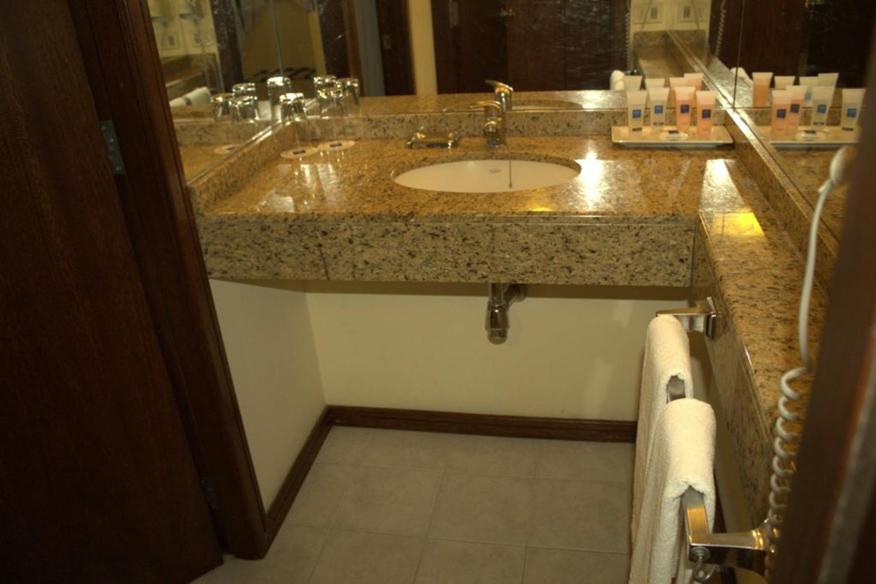Un bany amb un lavabo amb taulell de granat, un mirall i una barra de tovalloles.