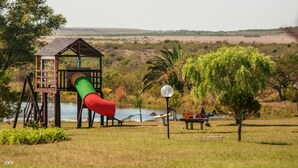 A playground with a slide and swings, a small building, and a lamp post. - Arapey Thermal Resort & Spa (Termas del Arapey)
