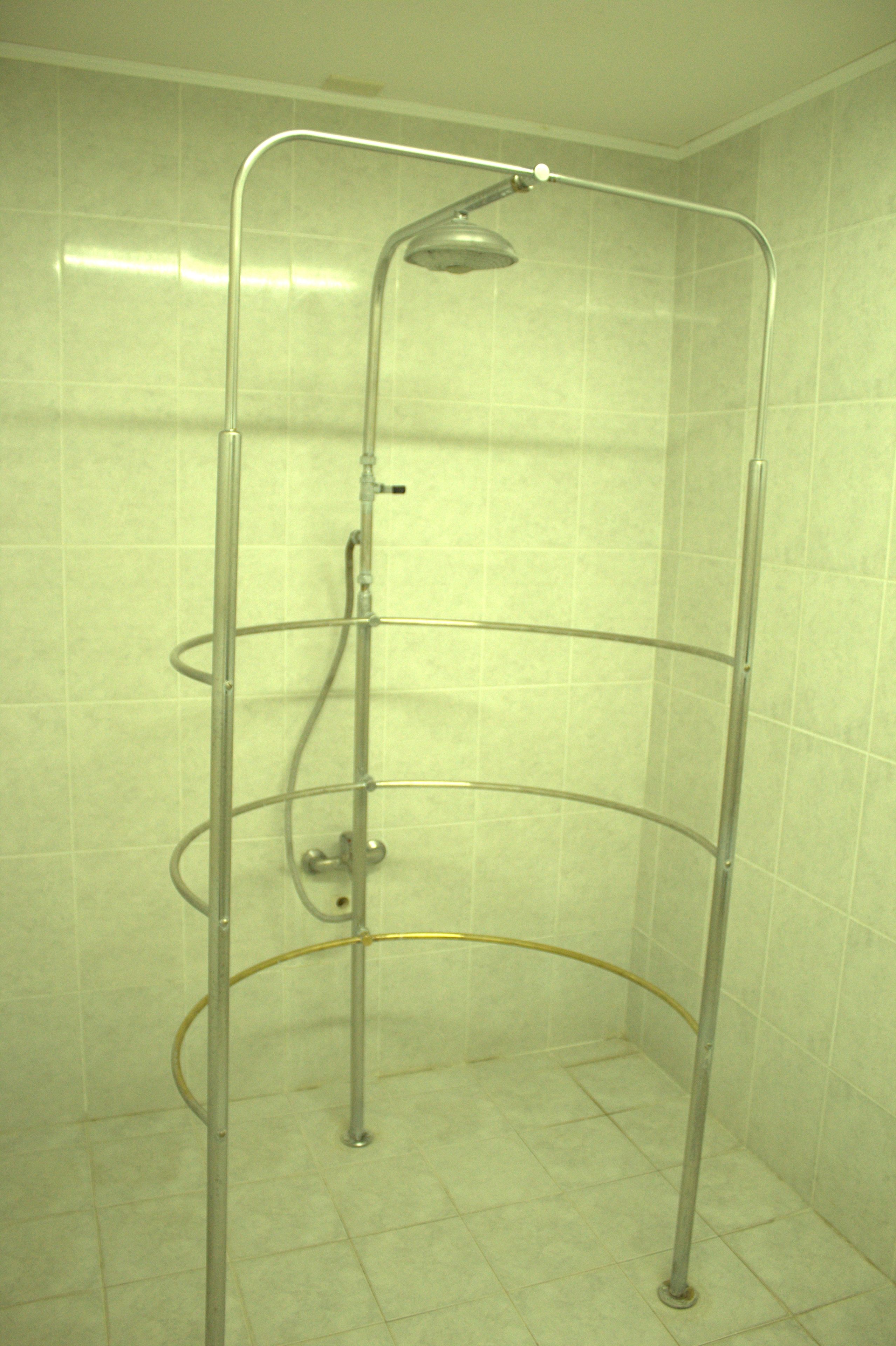 A shower enclosure with a metal frame and a handheld showerhead.