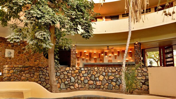 A spa area with a stone wall, a pool, and a ceiling fan. - Hwange Safari Lodge (Dete)
