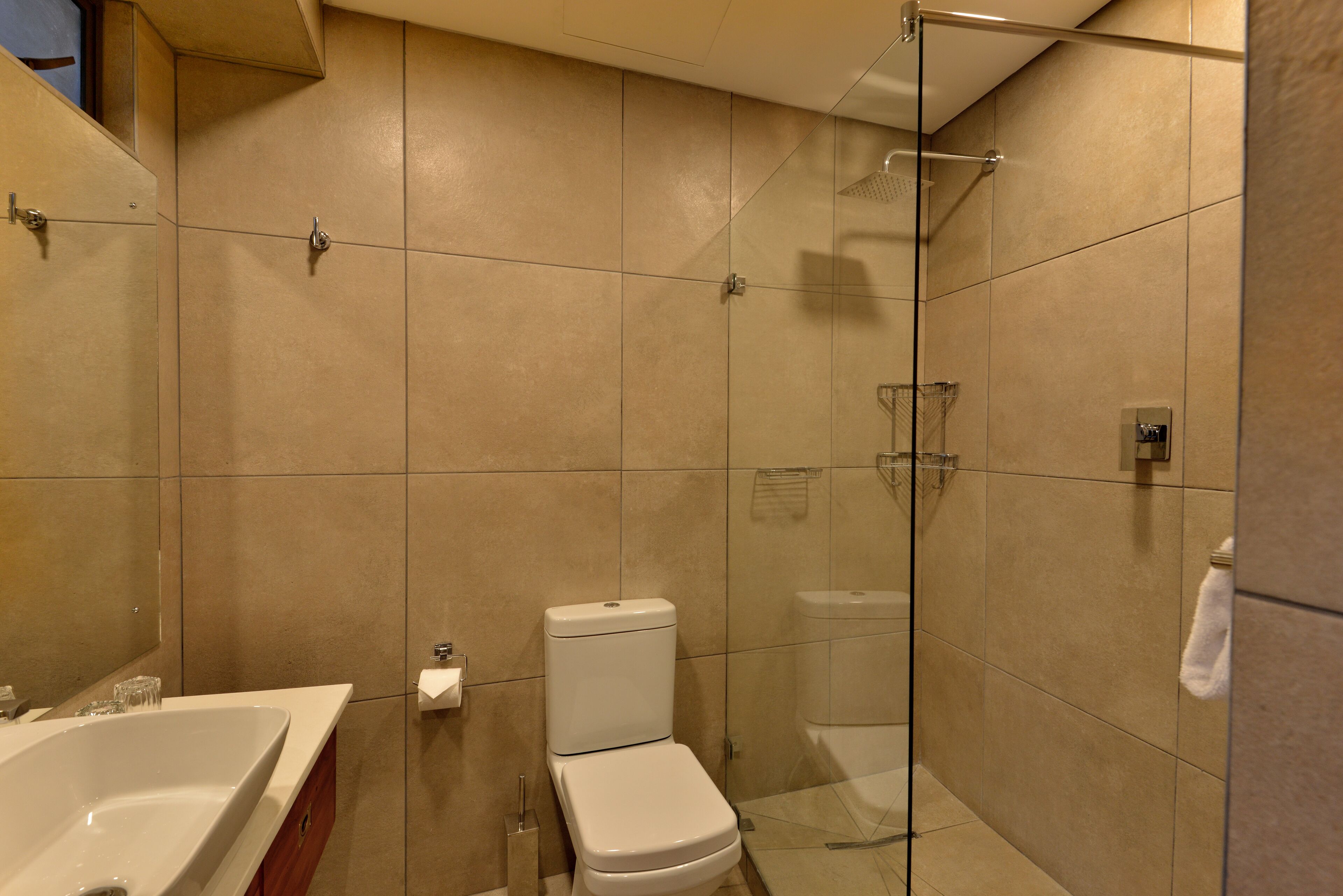 A modern bathroom with a bathtub, toilet, and glass shower enclosure.