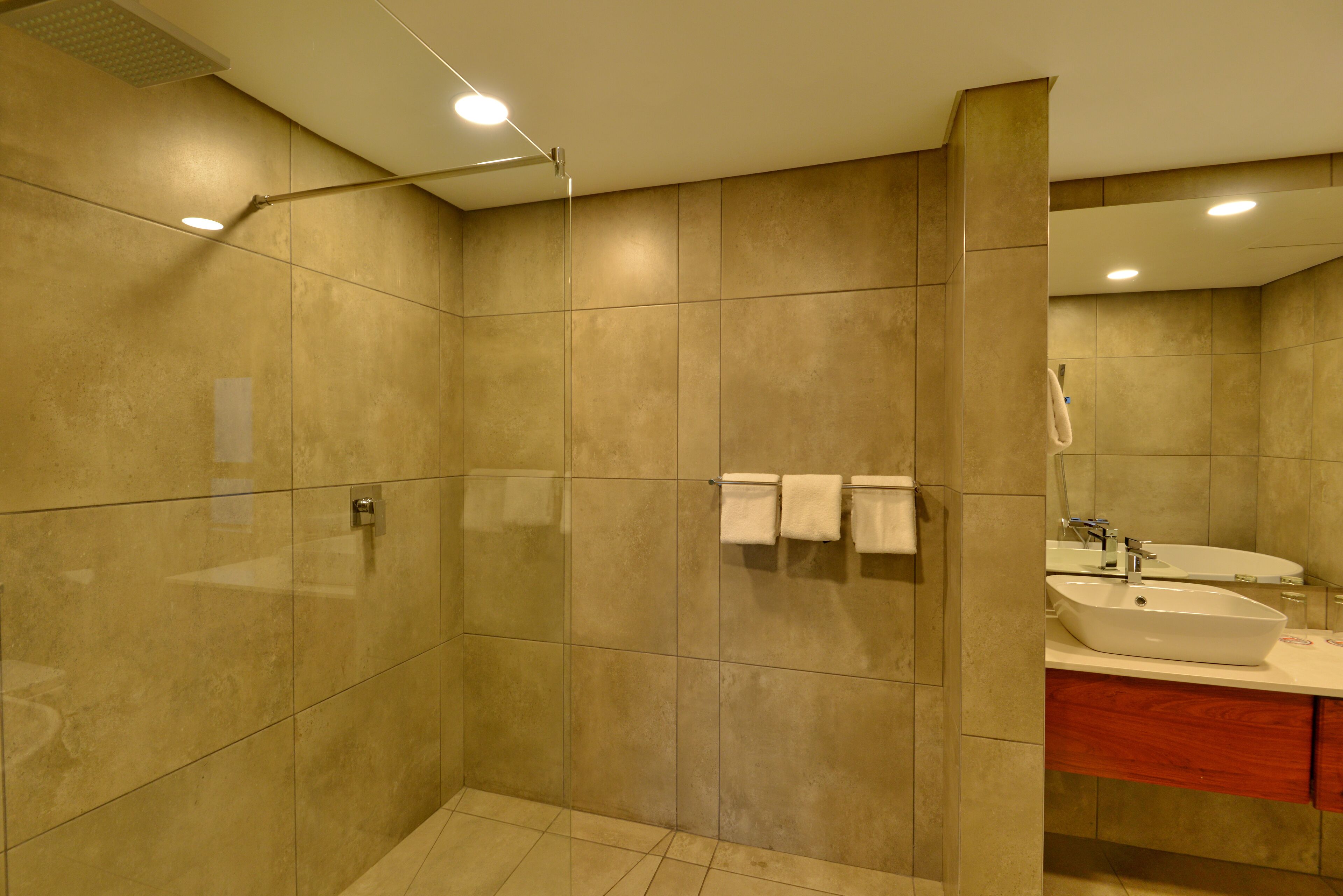Un baño moderno con cabina de ducha, tocador con lavabo y espejo.
