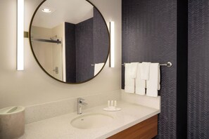 Un baño moderno con un espejo redondo, un lavabo y un perchero para toallas.