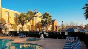 A hotel with a swimming pool, lounge chairs, and palm trees. - Fairfield Inn & Suites by Marriott Napa American Canyon (American Canyon)