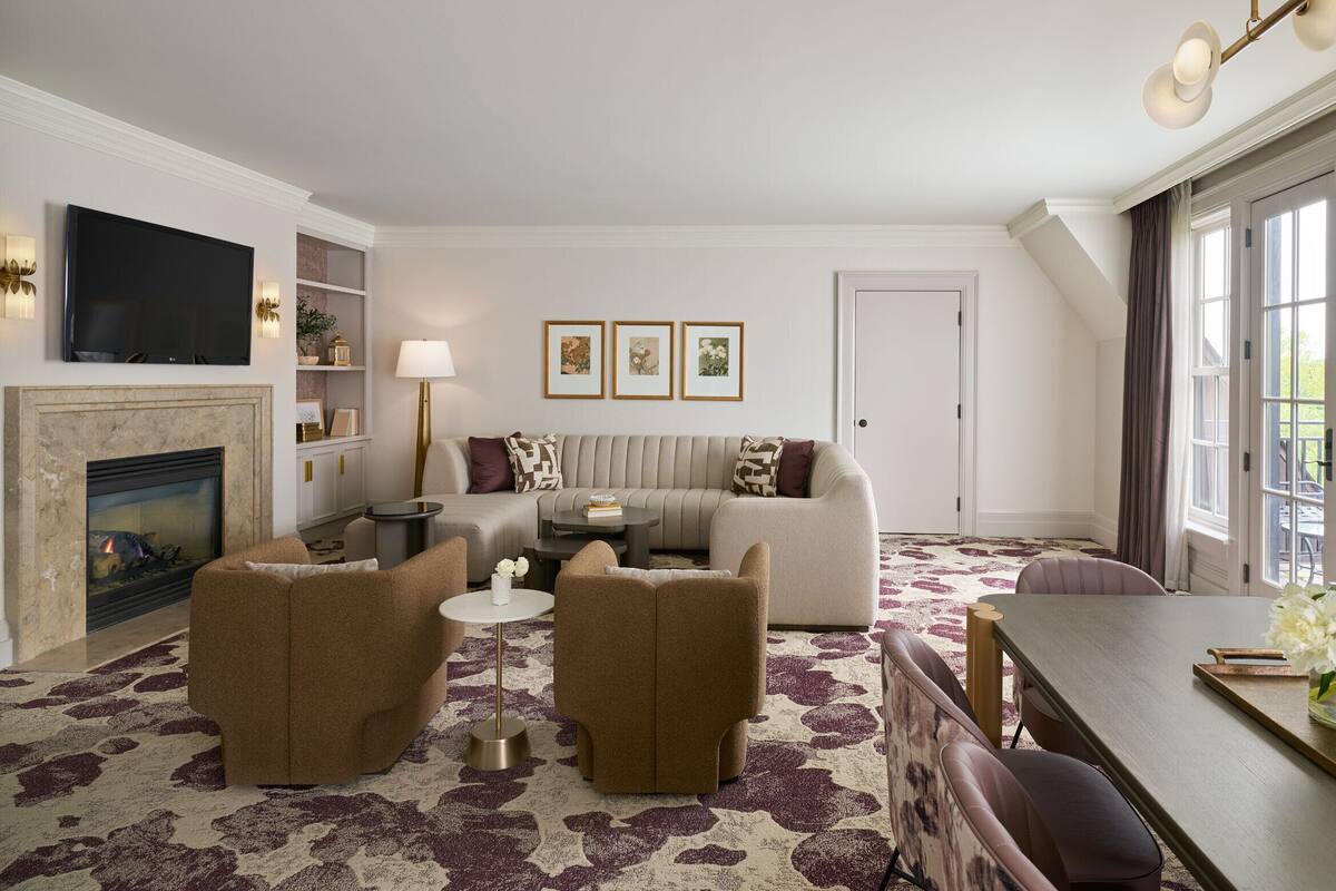 A living room with a fireplace, sofa, armchairs, and a dining table.