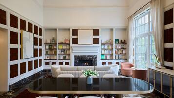 A spacious living room with a fireplace, a round glass table, and a comfortable seating area.