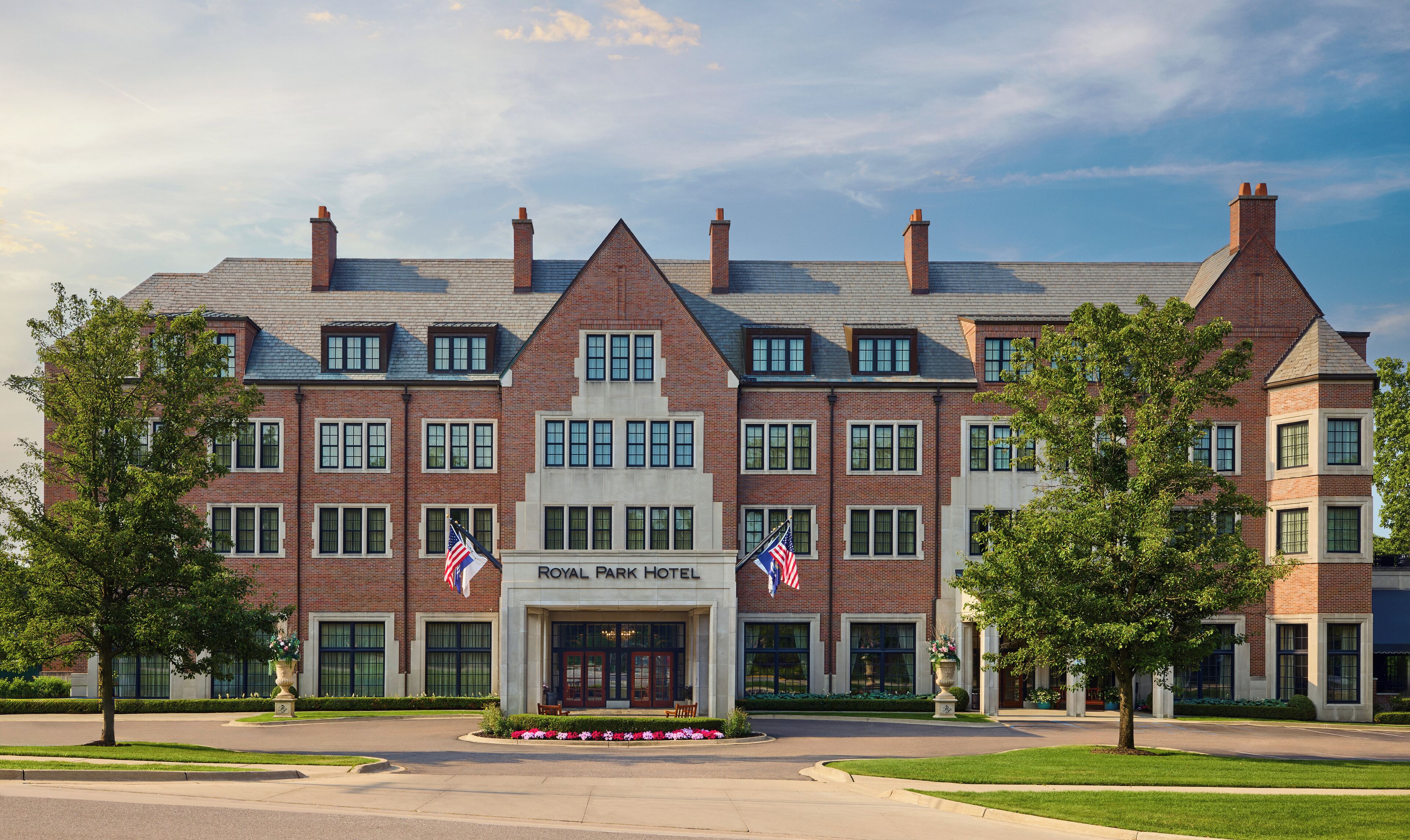 A large brick building with a symmetrical facade, multiple windows, and two American flags.