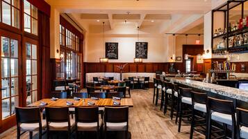 A restaurant with wooden tables and chairs, a bar area, and a menu board.