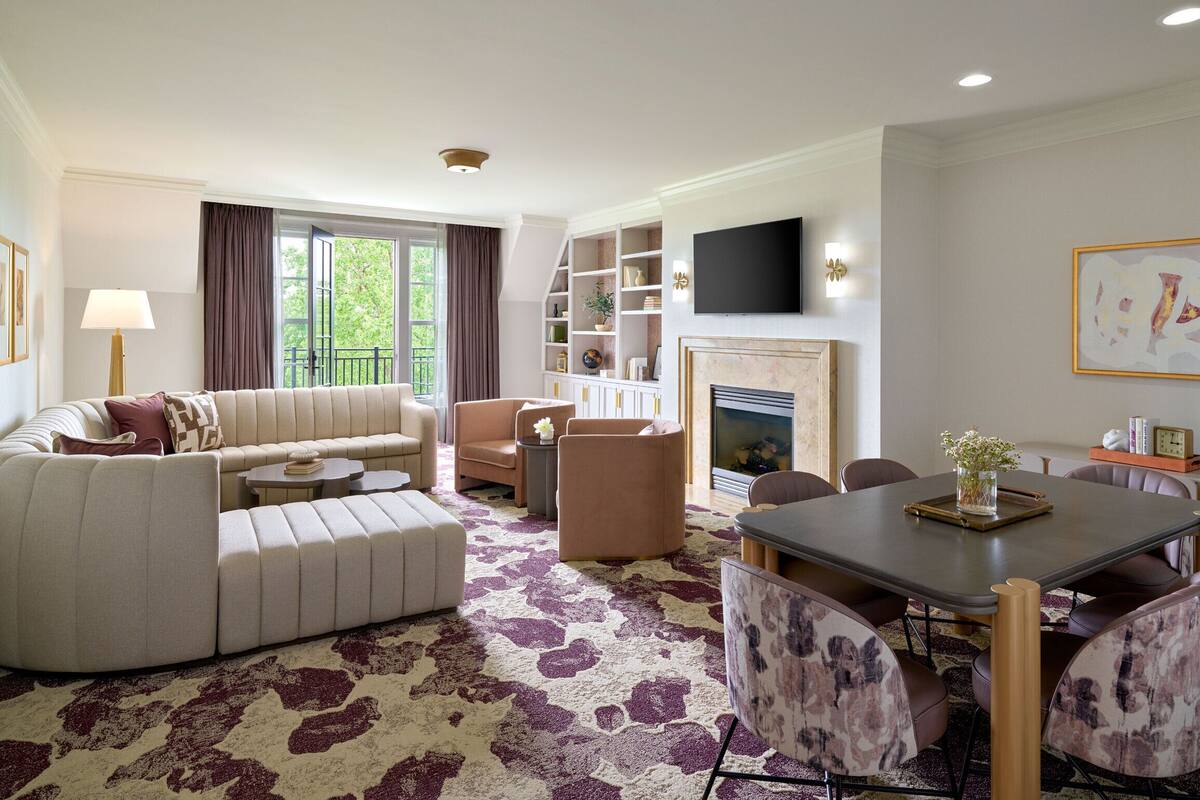 A modern living room with a sofa, armchairs, a fireplace, and a dining area.
