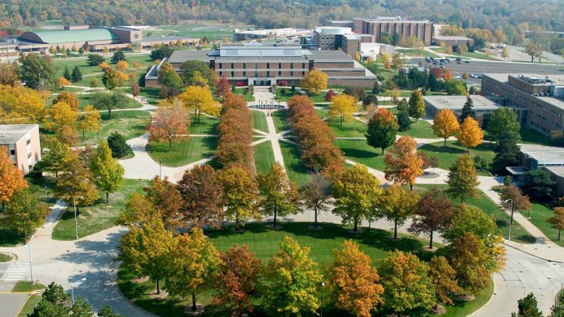 An aerial view of a campus with multiple buildings, green lawns, and trees with autumn foliage.
