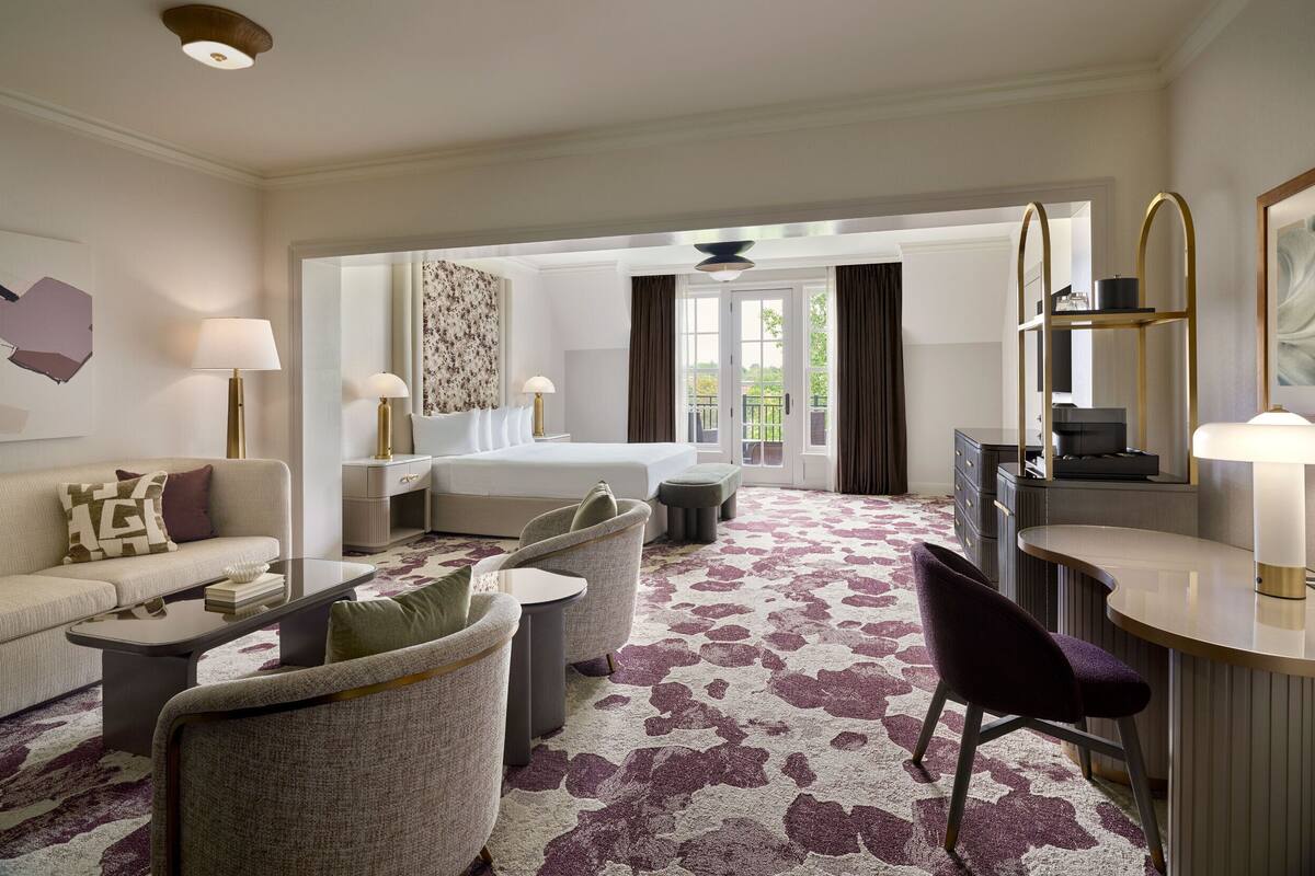 A hotel room with a sofa, chairs, a desk, and a bed.