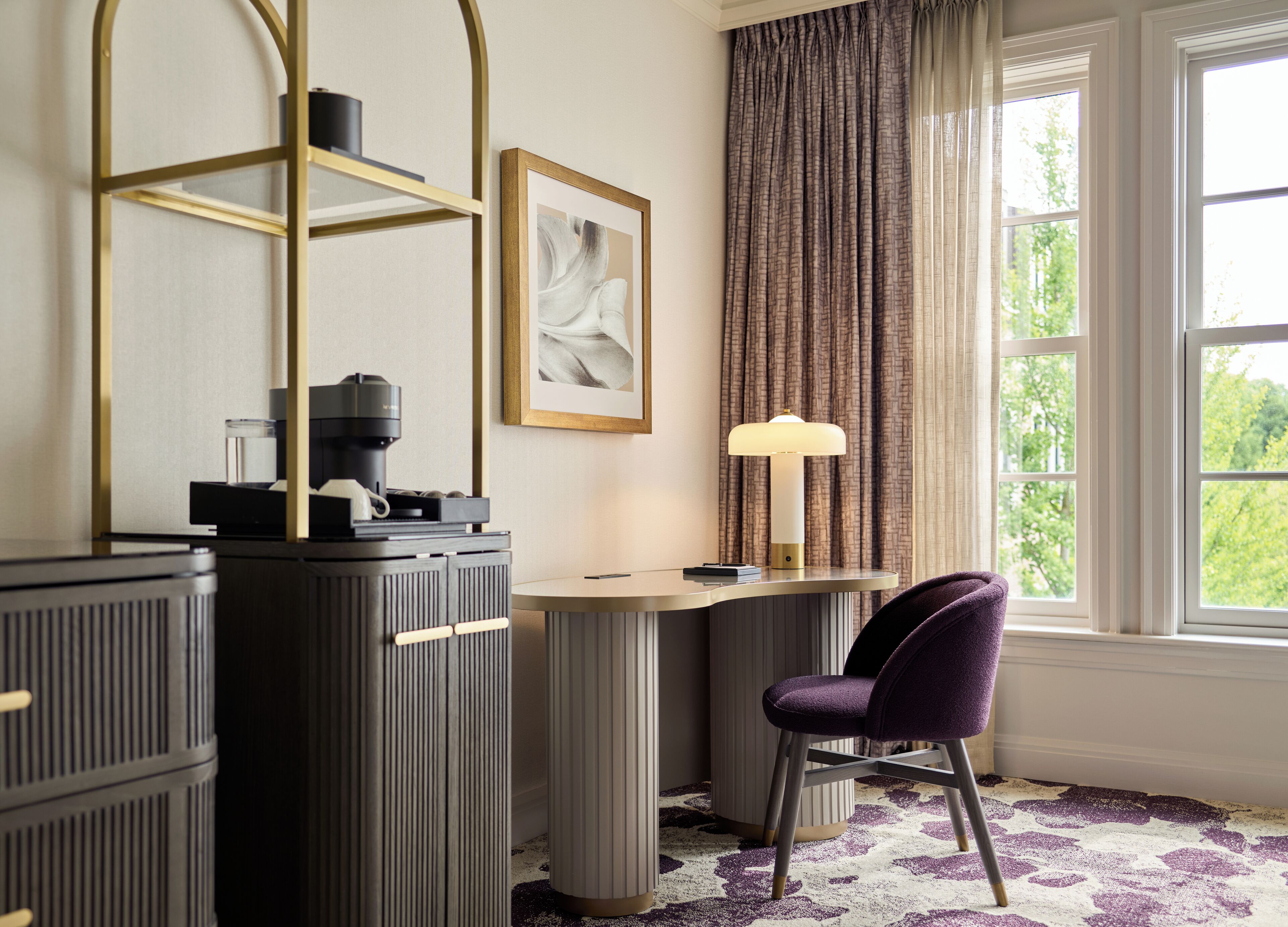 A modern room with a desk, a chair, a lamp, and a window with curtains.