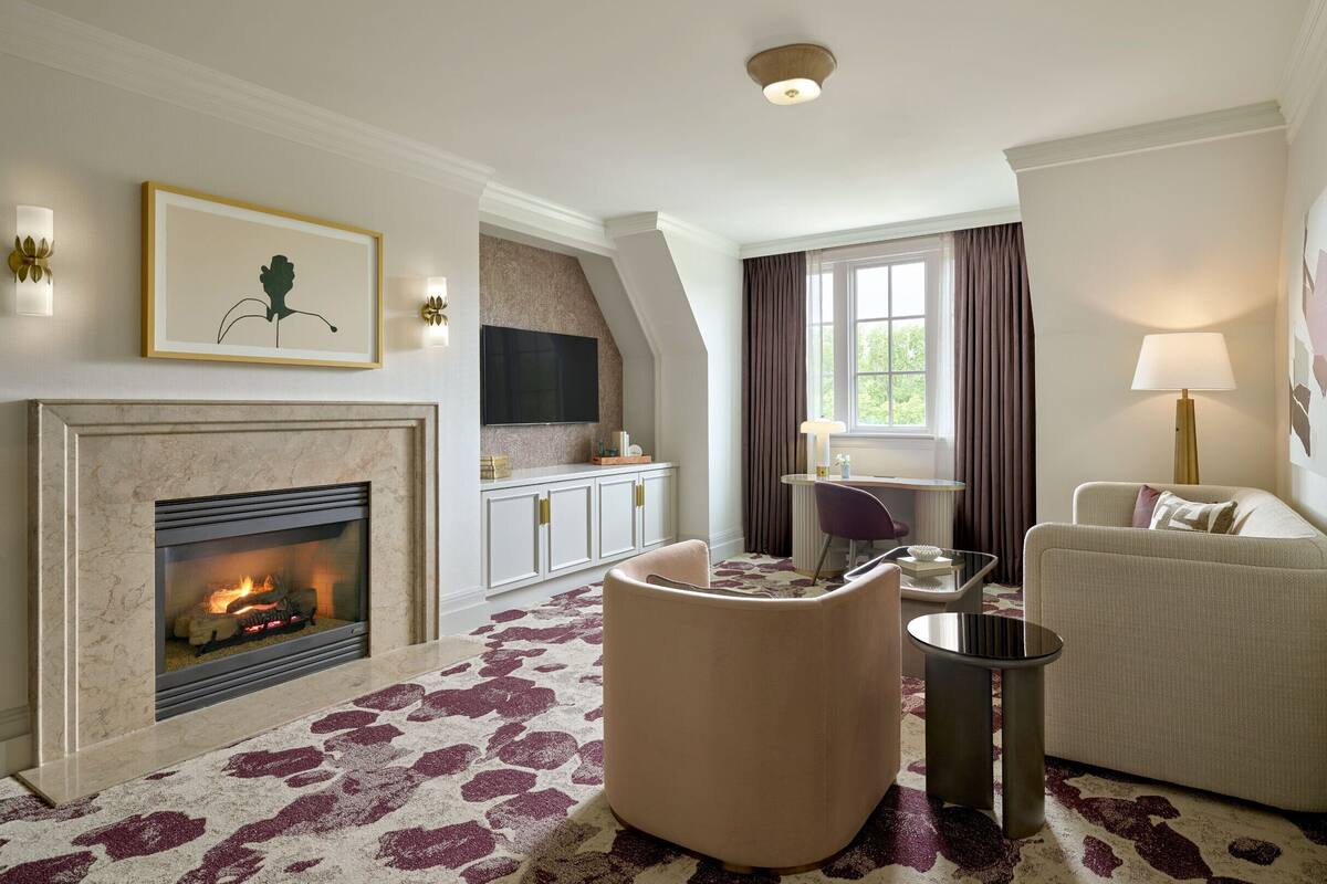 A living room with a fireplace, a sofa, a chair, a small table, and a lamp.