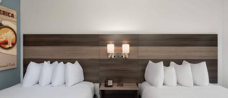 Una habitación de hotel con dos camas, un cabecero de madera, una mesita de noche con teléfono y un cartel en la pared.