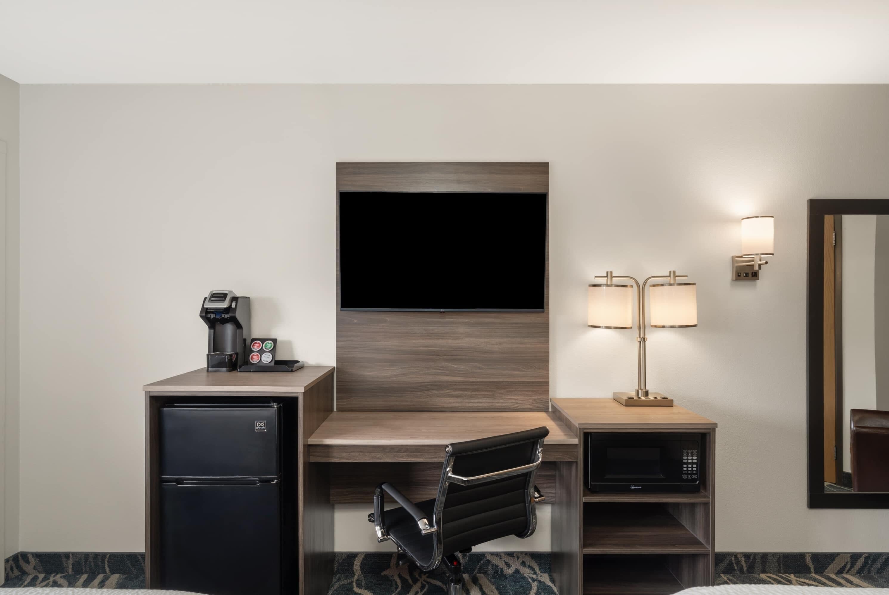 Une chambre d’hôtel équipée d’un bureau, d’une télévision à écran plat, d’un mini-réfrigérateur, d’une machine à café, d’une lampe, d’un four à micro-ondes et d’un lit.