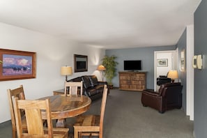 A living room with a round wooden table, two leather sofas, a TV, and a cabinet.