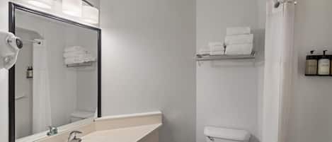A bathroom with a sink, mirror, towel rack, toilet, and shower curtain.