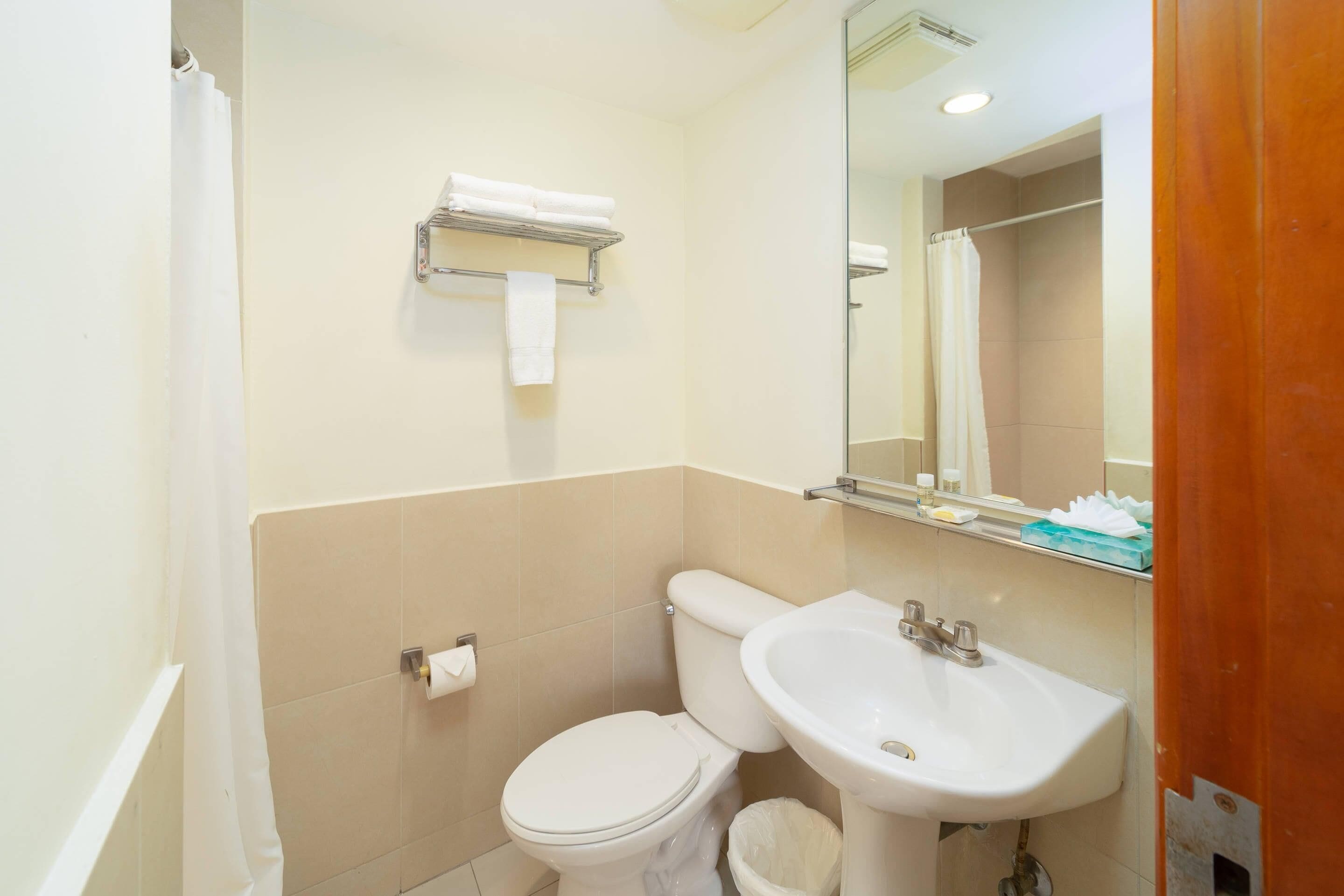 Un baño con inodoro, lavamanos y perchero para toallas.